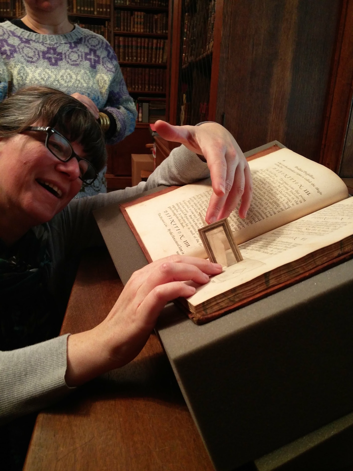 "Laura lifting the flaps of Joseph Moxon, Practical perspective (London, 1670), Christ Church Library, OR.2.9 (under Cristina's watchful eyes)"